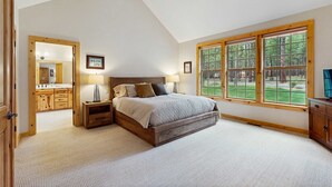 Ein Schlafzimmer mit Bett, Deckenventilator, großem Fenster und Blick ins Freie.