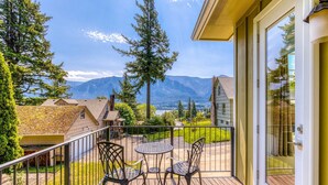 Ein Balkon mit Tisch und Stühlen, Blick auf Berge und ein Haus im Hintergrund.