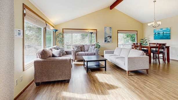 Un salon spacieux avec un plafond haut, de grandes fenêtres et un coin repas doté de meubles en bois.