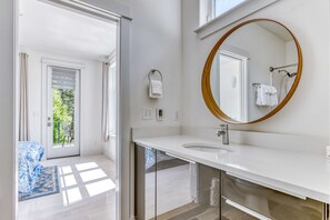 A modern bathroom with a large mirror, a white sink, and a glass shower enclosure. - Mountain and river-view home & studio with fireplace, grills, outdoor areas (Stevenson)
