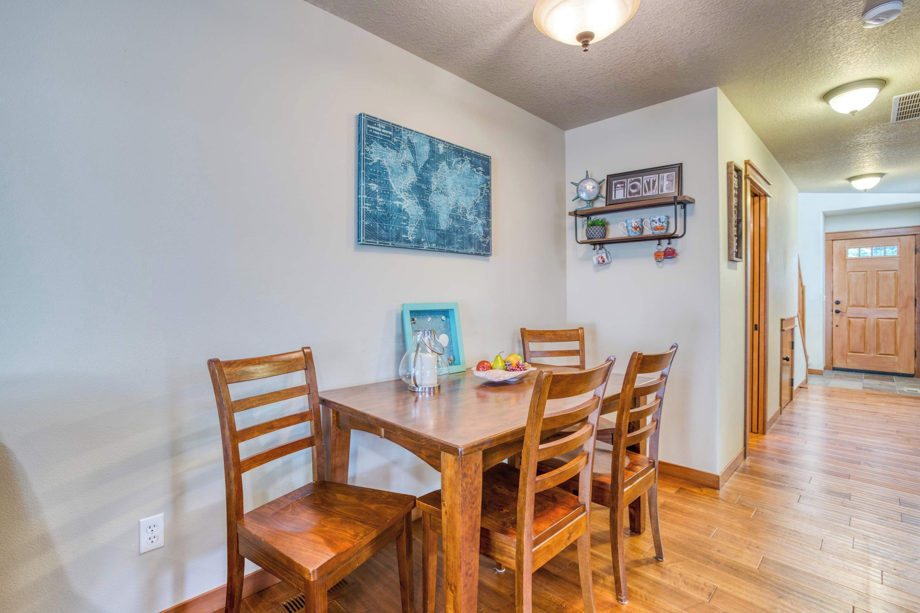 A dining area with a wooden table and chairs, a world map on the wall, and a shelf with decorative items.