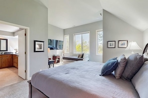 A bedroom with a large bed, a desk, and a window. - Charming home with private hot tub, shared pool, & SHARC access (Sunriver)