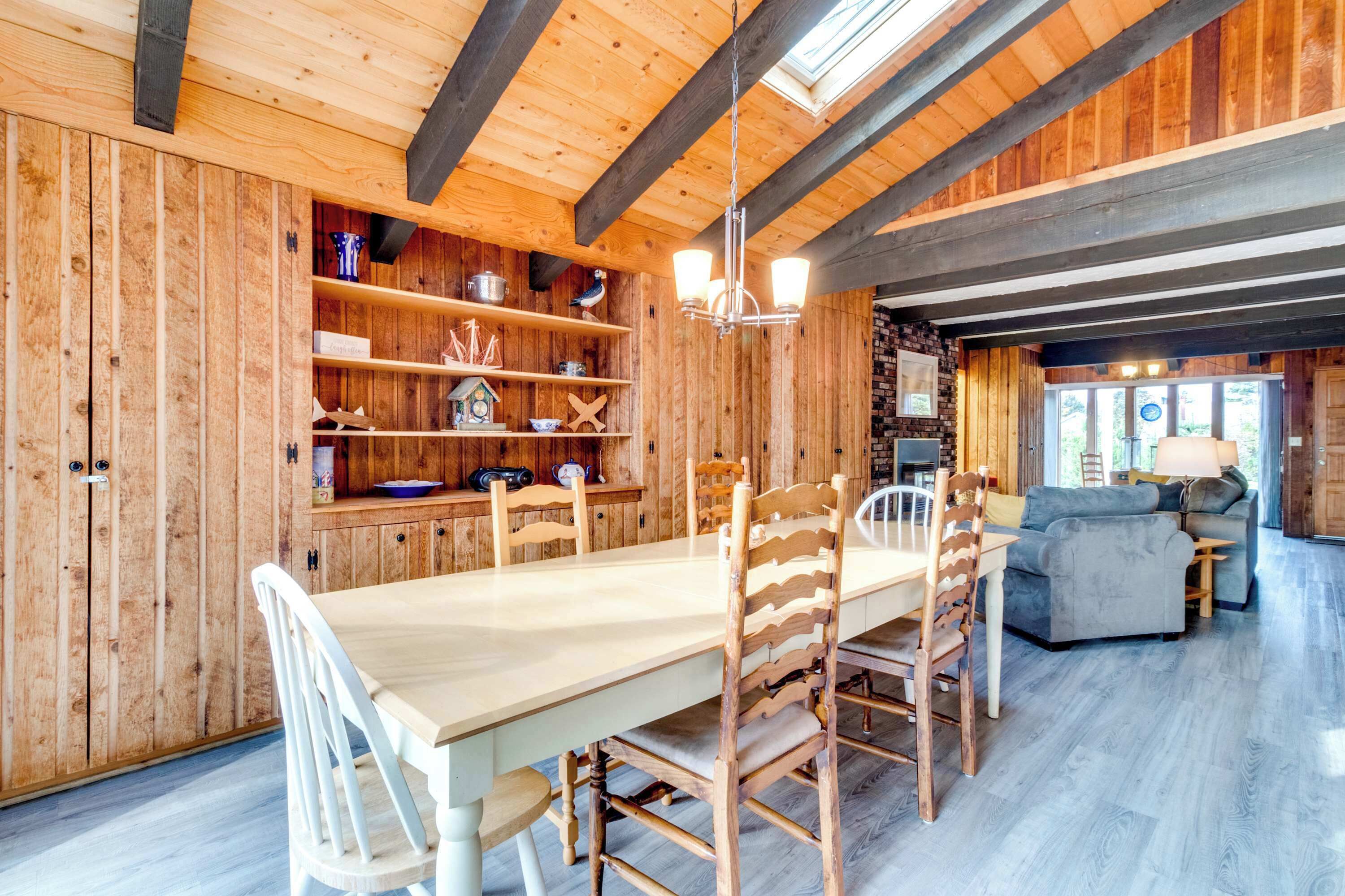 A wooden interior with a dining table, chairs, and a sofa.