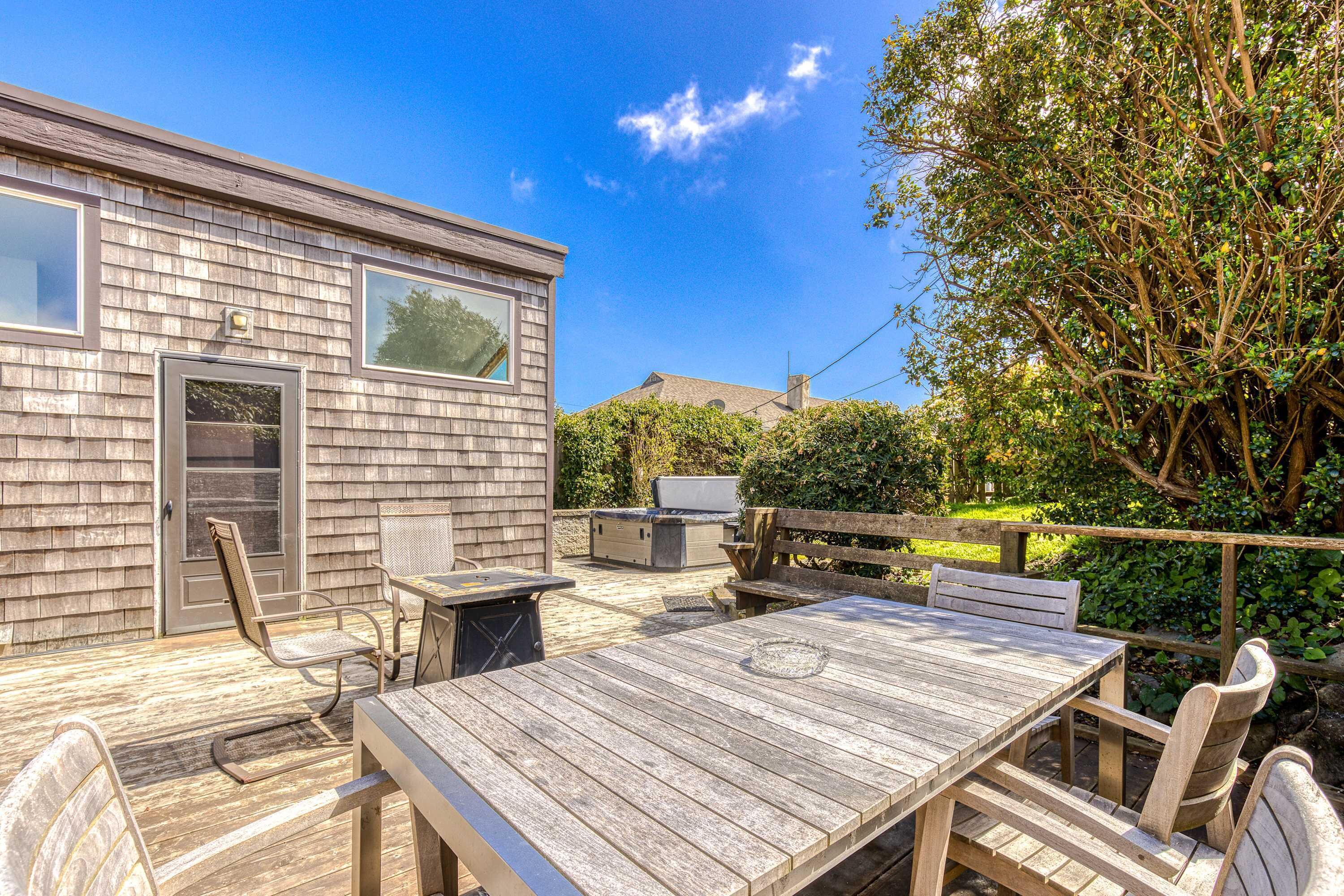Une terrasse en bois avec une table et des chaises, un barbecue et une porte-fenêtre coulissante.