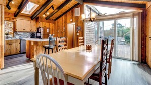A wooden interior with a kitchen, dining area, and large sliding glass doors to a deck.