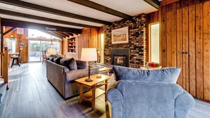 A cozy living room with a fireplace, wooden walls, and a sofa.