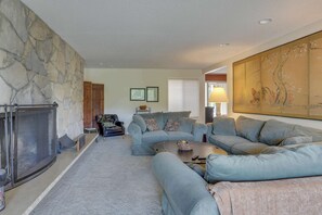 A living room with a stone fireplace, a large sectional sofa, a coffee table, and a traditional Japanese screen.