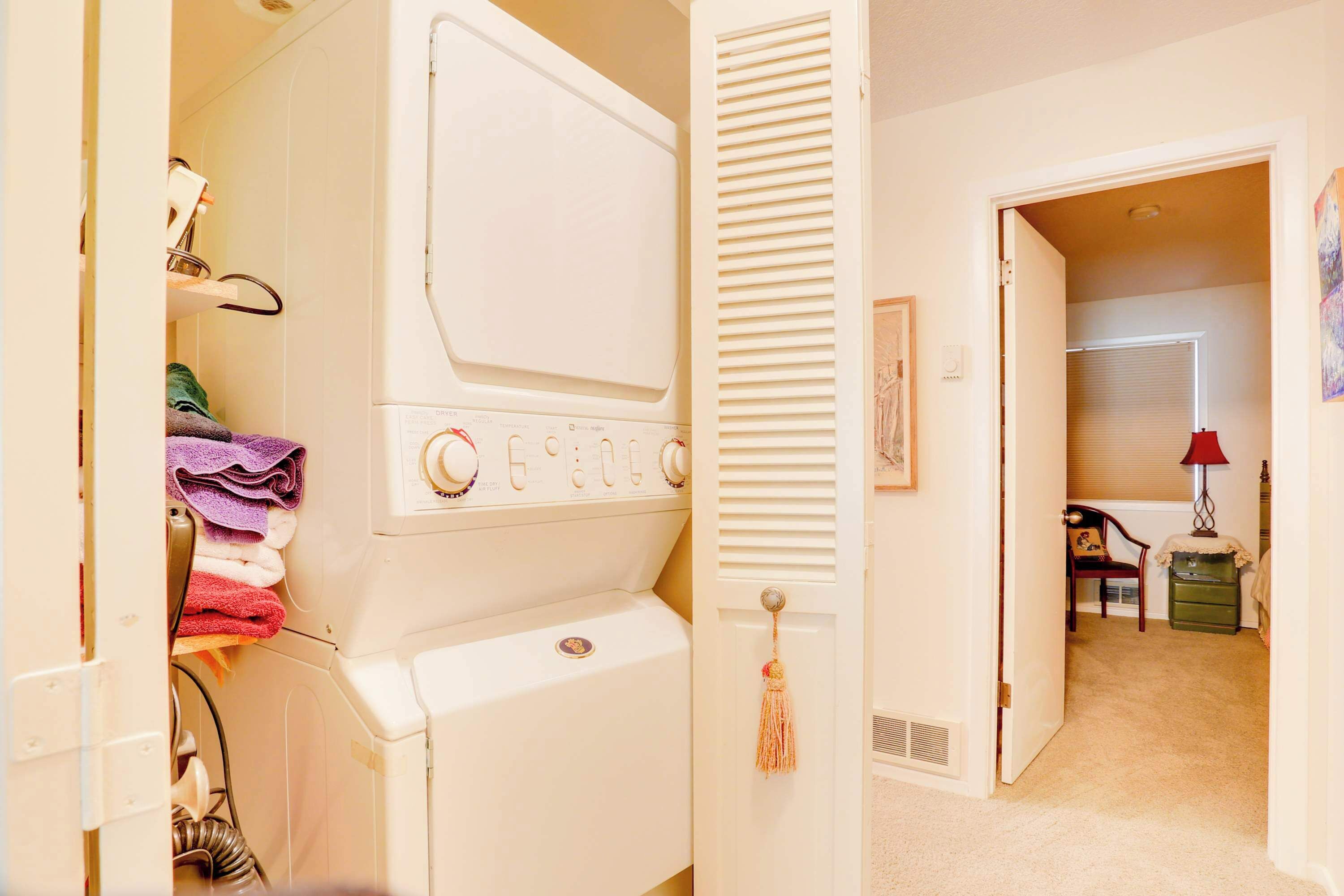 Un cuarto de lavandería con lavadora, secadora y una puerta que da a otra habitación.