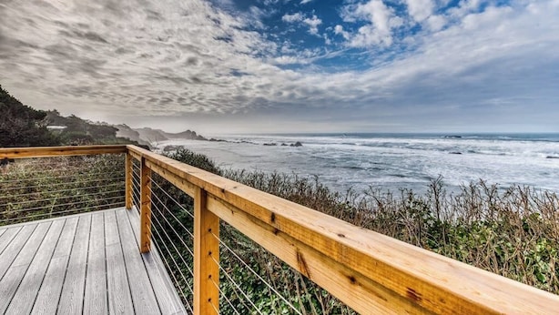 Terraza de madera con barandilla y vistas al mar.