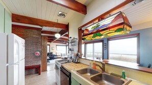 Una cocina con encimera de madera, pileta de acero inoxidable y un ventanal de vidrio emplomado de colores.