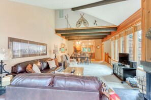 A living room with a brown leather sofa, a wooden coffee table, a fireplace, and a dining area with a table and chairs. - Beautiful & dog-friendly condo with shared pool/hot tub, central AC & fireplace (Sunriver)