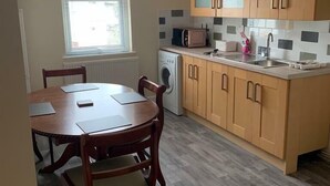 Eine kompakte Küche mit Holzschränken, einer Mikrowelle, einer Waschmaschine und einem Essbereich mit Tisch und Stühlen.