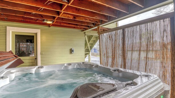 Un bain à remous avec un siège en pierre, un plafond en bois et un mur extérieur de couleur verte.