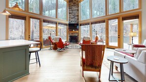 Un vaste espace de vie doté de grandes fenêtres, d’une cheminée et de meubles modernes.