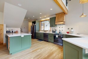 A kitchen with a central island, wooden cabinets, and a window with blinds.
