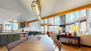 Une cuisine spacieuse avec une longue table à manger, des meubles en bois et de grandes fenêtres.