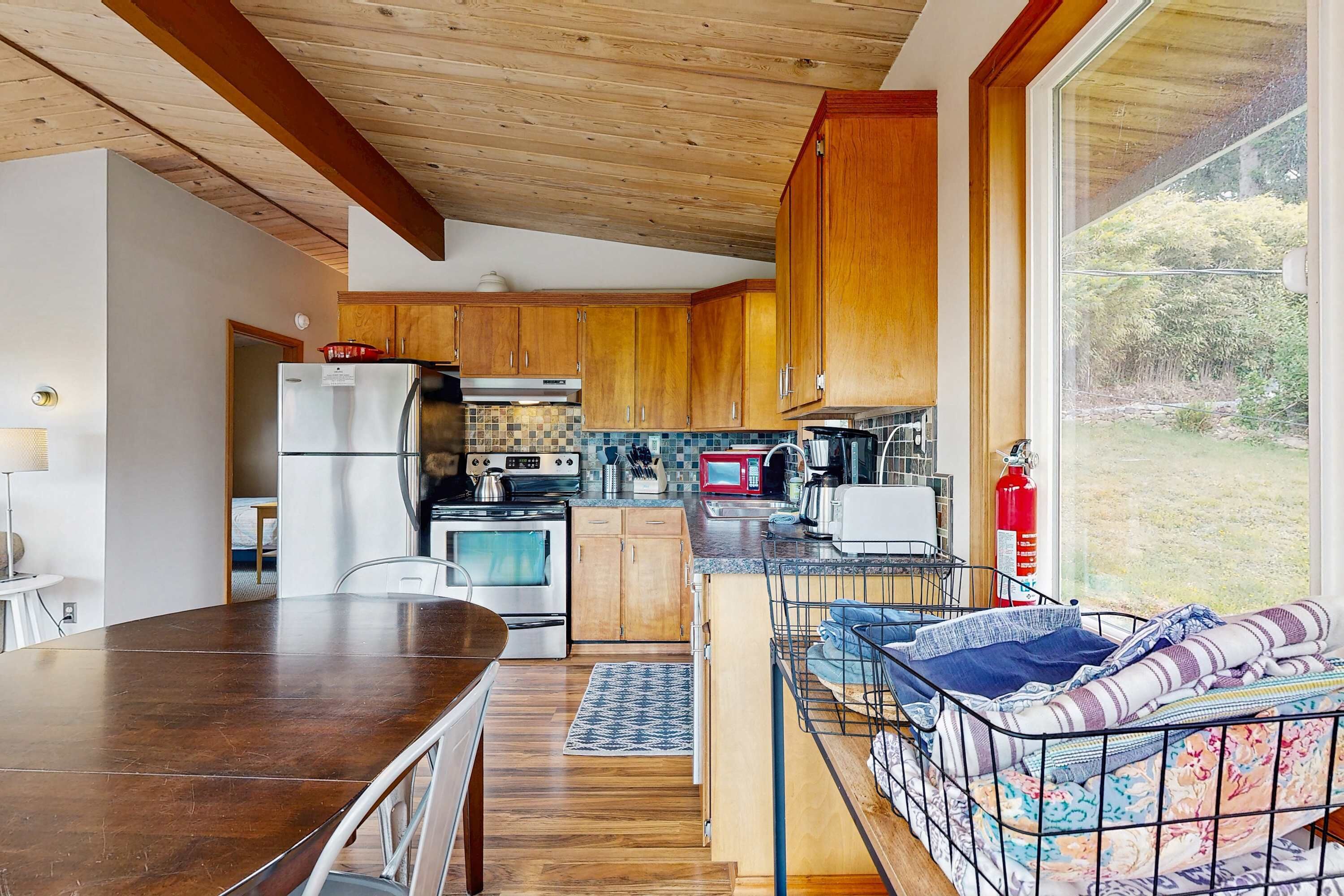 Una cocina moderna con armarios de madera, una mesa de comedor y un sofá con estructura metálica.