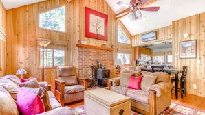 A cozy cabin interior with a fireplace, wooden walls, a dining area, and a large window. - Modern, cozy, dog-friendly mountain retreat in central location (Rhododendron)