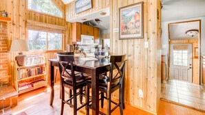 A wooden interior with a dining table, chairs, a bookshelf, a kitchen area, and a door leading to another room. - Modern, cozy, dog-friendly mountain retreat in central location (Rhododendron)