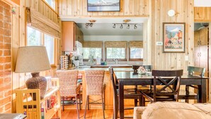 A wooden interior with a dining area, kitchen, and a bookshelf. - Modern, cozy, dog-friendly mountain retreat in central location (Rhododendron)