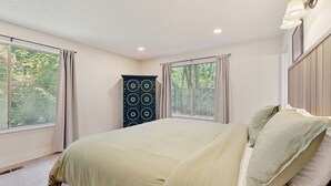 A bedroom with a bed, two windows with curtains, a cabinet, and a wall-mounted light fixture. - Spacious home with full kitchen, wifi, private backyard & grill (Welches)