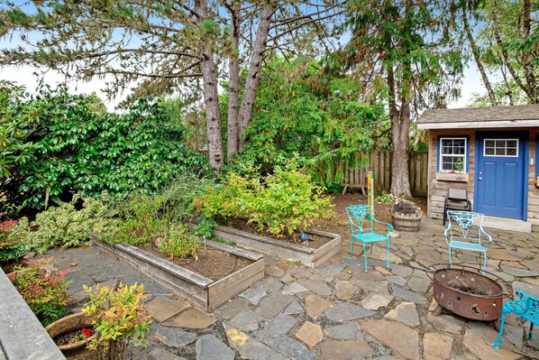 A garden with raised beds, a blue door, and outdoor furniture. - Dog-Friendly Home withFenced Oasis, Gas Grill - Walk Everywhere (Seaside)