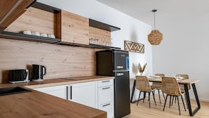 A modern kitchen with a black refrigerator, wooden cabinets, and a dining area with wicker chairs. - D52 Apartment Hotel (Budapest)