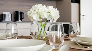 A dining table set with plates, glasses, and a vase of flowers. - D52 Apartment Hotel (Budapest)