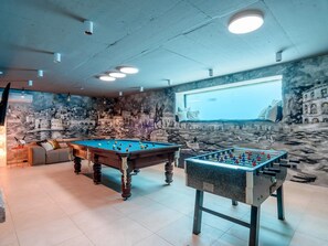 A room with two foosball tables, a pool table, a sofa, and a mural on the wall. - 5-bedroom Estate With Heated Pool (Kastela)