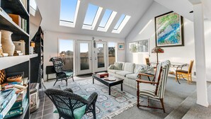 A spacious living room with a high ceiling, skylights, a sofa set, a coffee table, and a bookshelf. - Family-Friendly, Waterfront Home with Free WiFi, Gas Fireplace, & Private W/D (Long Beach)