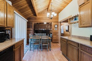 A wooden interior with a dining area, kitchen, and a clock on the wall. - Woodsy Cabin with Private Hot Tub, Game Tables & 8 SHARC Passes - Dogs OK (Sunriver)