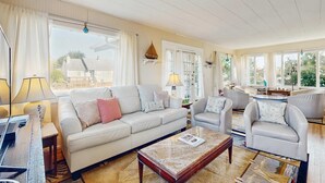 Een ruime woonkamer met een bank, fauteuils, een salontafel en een eethoek.