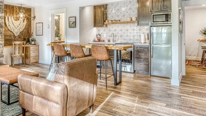 Une cuisine moderne avec des meubles en bois, un réfrigérateur en acier inoxydable et un coin repas doté de chaises en cuir.