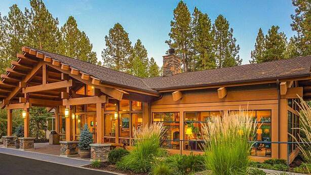Un chalet doté d’un patio couvert, de grandes fenêtres et d’une cheminée en pierre.