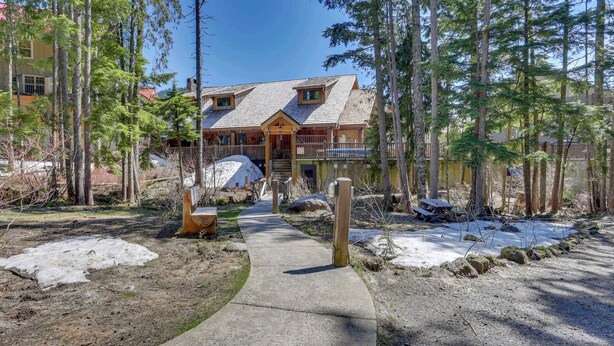 A lodge with a concrete path leading to the entrance, surrounded by trees and a snow-covered ground. - Riverfront mountain townhouse with pool & hot tub, patio, & easy ski access (Government Camp)