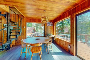 A wooden interior with a spiral staircase, a round table with chairs, and large windows offering a view of the outdoors. - Lakefront, dog-friendly home in Joseph with amazing yard, deck (Joseph)