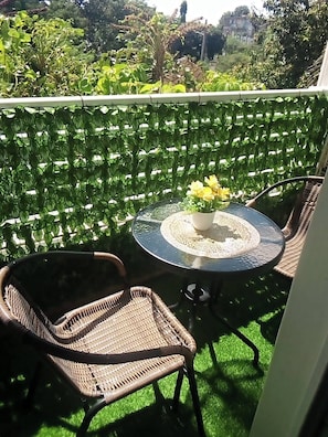 A balcony with a table, chairs, and a potted plant. - Jolly 1br With AC, Backup Gen, Netflix, Balcony (Kisumu)