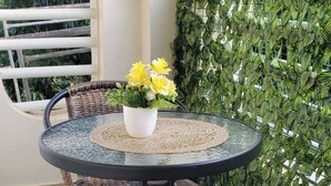 Mesa redonda com cadeiras, um vaso de planta e uma parede verde.