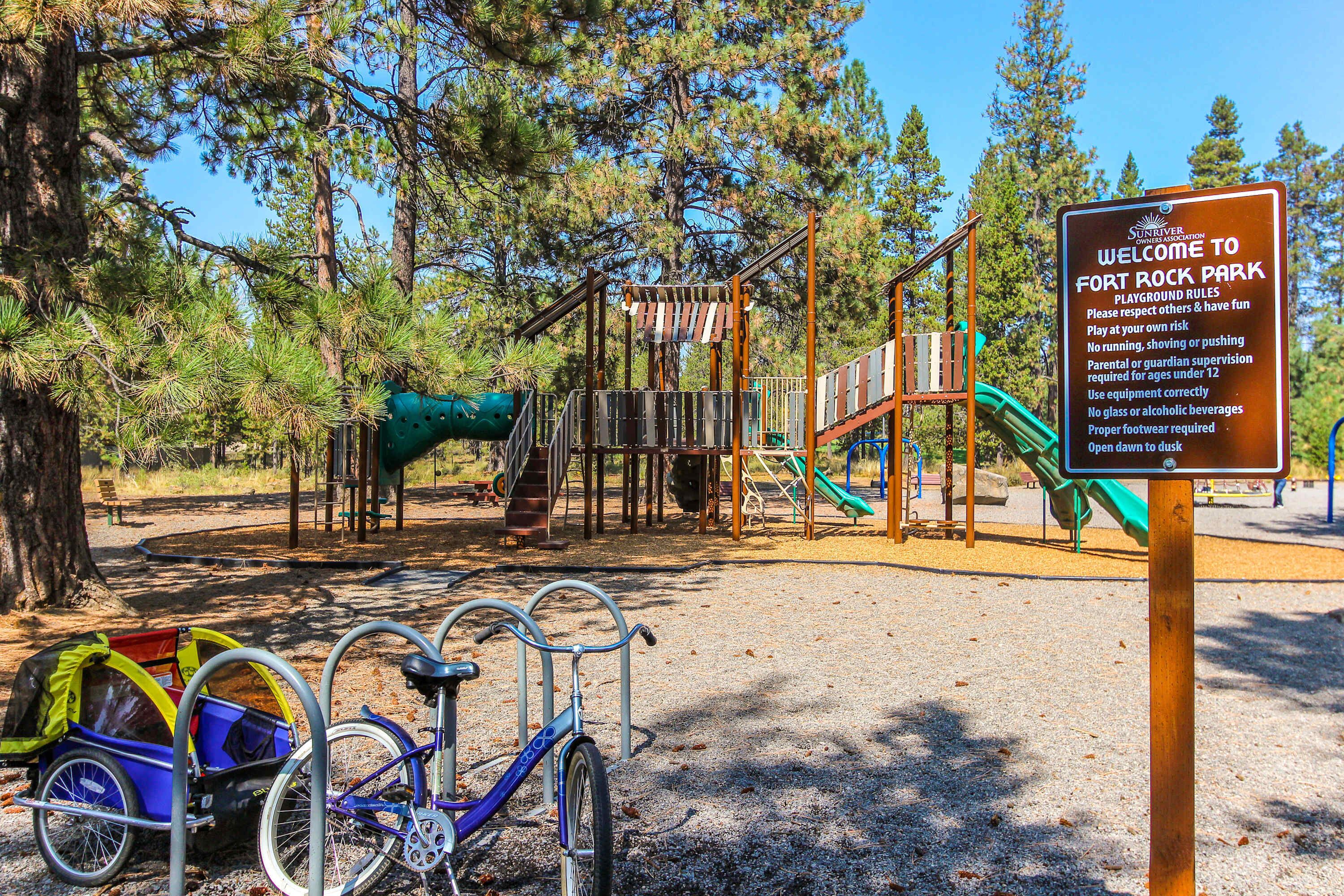Un parque infantil con un cartel, una bicicleta y un cochecito.