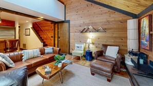 A cozy living room with leather sofas, a coffee table, a fireplace, and a staircase leading to an upper level. - in Sunriver with SHARC amenities, washer&dryer, & dog-friendly (Sunriver)
