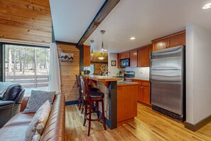 Eine Küche mit Holzausstattung, einem Edelstahlkühlschrank und einer Bar mit Hockern.