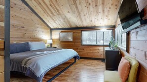 A wooden cabin interior with a bed, a sofa, a desk, and a window with blinds. - in Sunriver with SHARC amenities, washer&dryer, & dog-friendly (Sunriver)