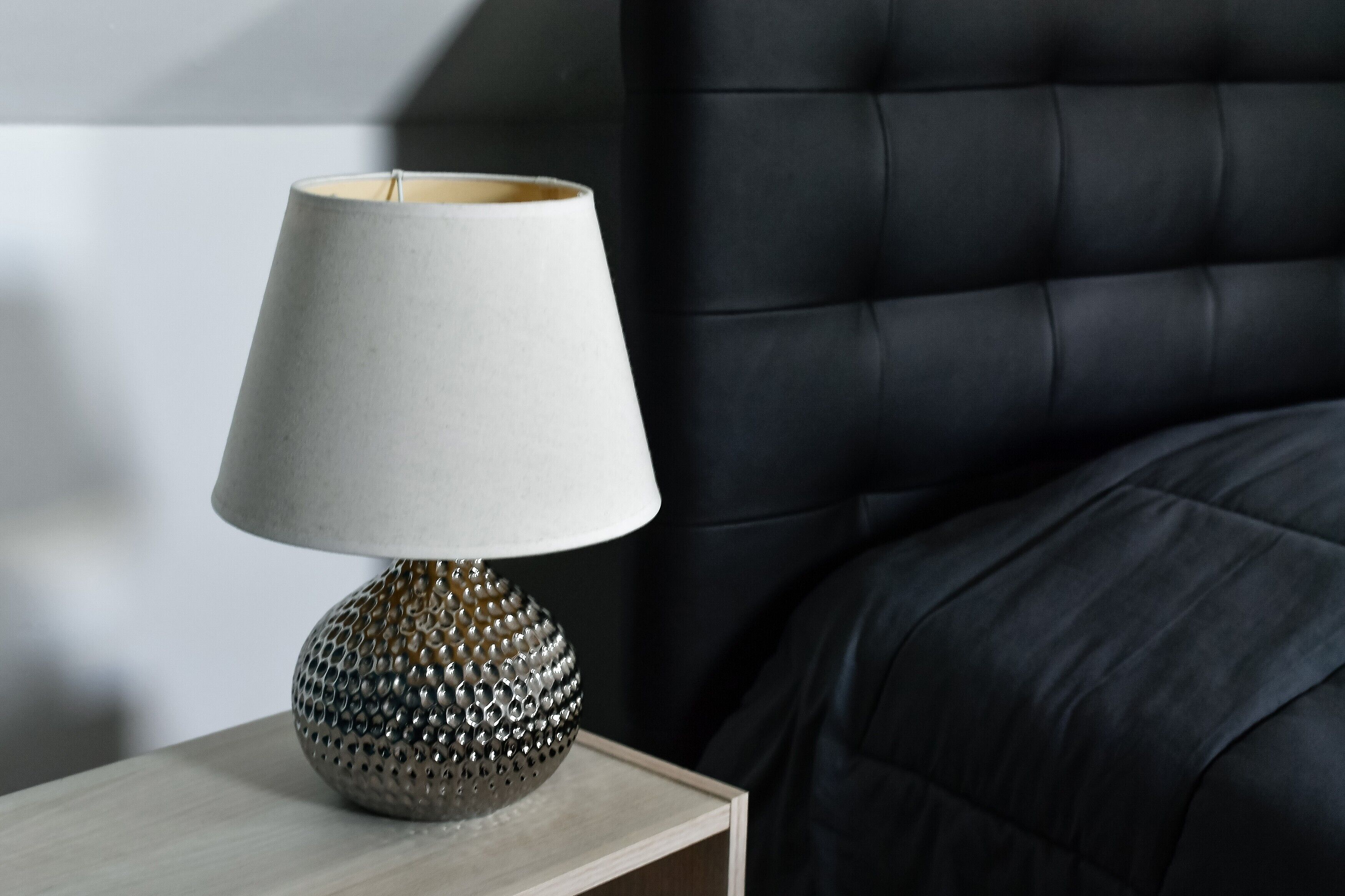 A lamp with a textured base on a bedside table.