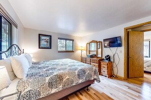 Ein Schlafzimmer mit Bett, Schminktisch, Fernseher und einer Tür zu einem anderen Raum.