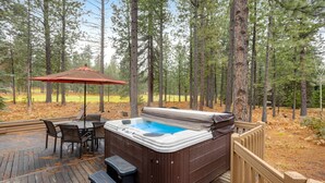 A hot tub on a wooden deck surrounded by tall pine trees. - Forested getaway with kitchen, stone fireplace, pool, & private hot tub (Black Butte Ranch)