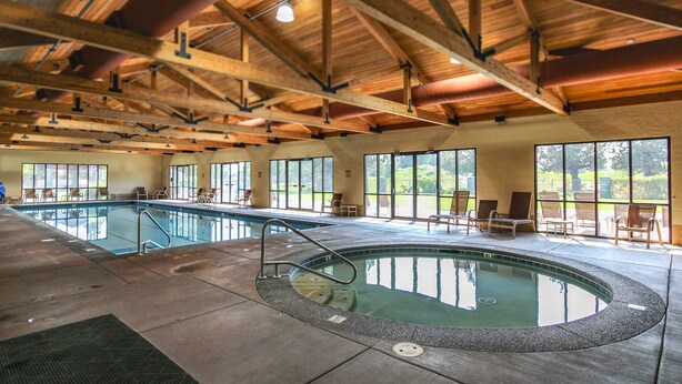 An indoor swimming pool with a wooden ceiling and large windows. - Two-story townhome on Ridge Golf Course with pools, hot tubs, gyms, tennis (Eagle Crest)