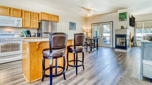 A modern kitchen with wooden cabinets, a central island with bar stools, a microwave, stove, and a ceiling fan. - Two-story townhome on Ridge Golf Course with pools, hot tubs, gyms, tennis (Eagle Crest)