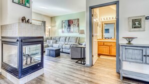 A living room with a fireplace, a sofa, and a kitchen area visible through an open doorway. - Two-story townhome on Ridge Golf Course with pools, hot tubs, gyms, tennis (Eagle Crest)