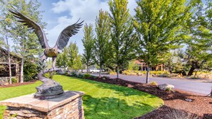 A landscaped area with a stone structure, a metal eagle sculpture, and a road in the background. - Two-story townhome on Ridge Golf Course with pools, hot tubs, gyms, tennis (Eagle Crest)