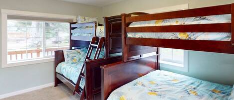 A bedroom with two bunk beds, a window with a view, and a door.